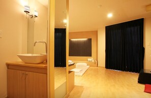 A modern bathroom with a large sink, wooden cabinet, and a mirror. There is a shower area with a curtain and a towel on the floor. - We Motel (Pyeongchang)