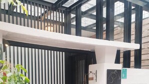 Una entrada moderna a un edificio con un portón negro, un pequeño césped y una planta en maceta.