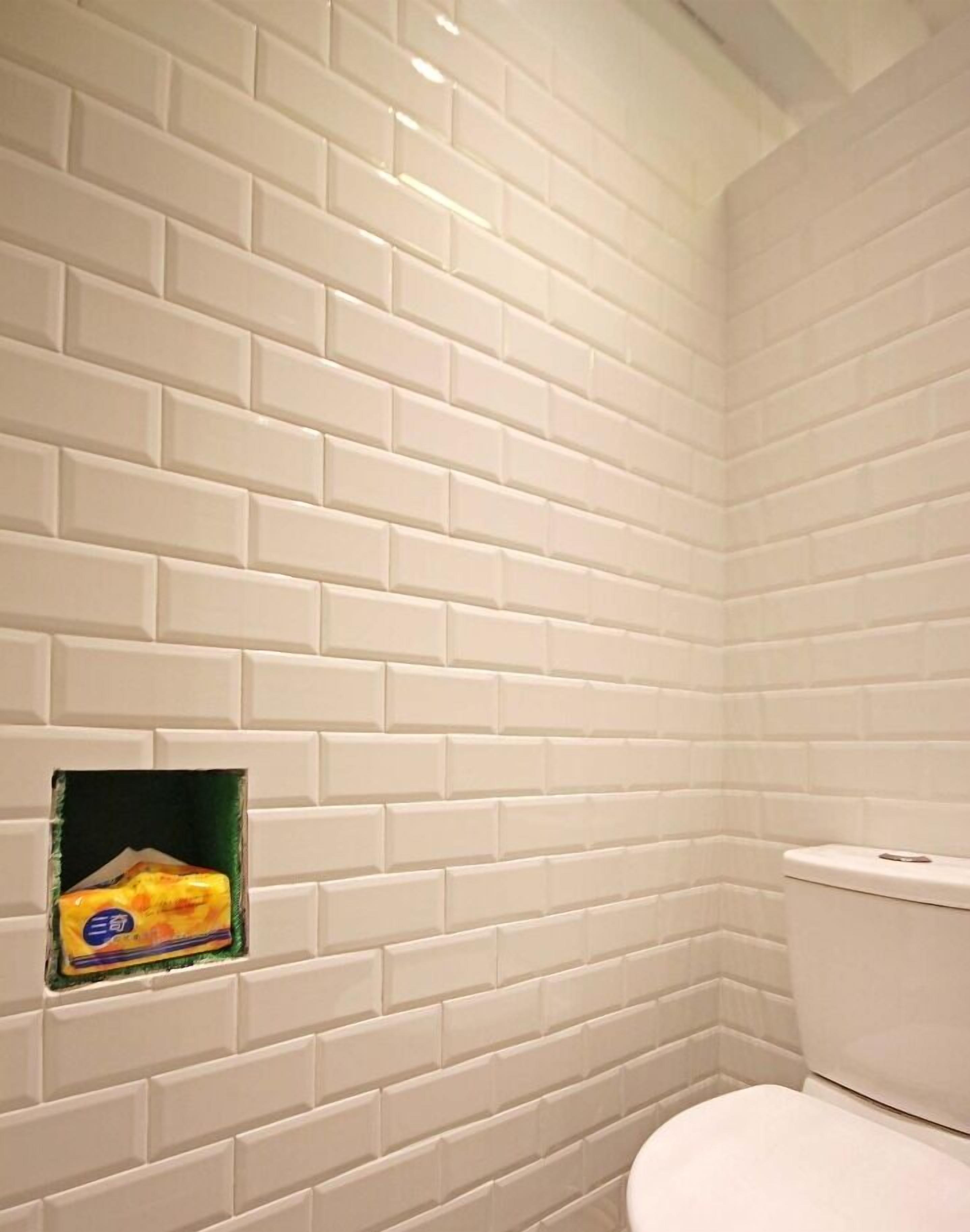 A bathroom with white subway tile walls and a toilet.