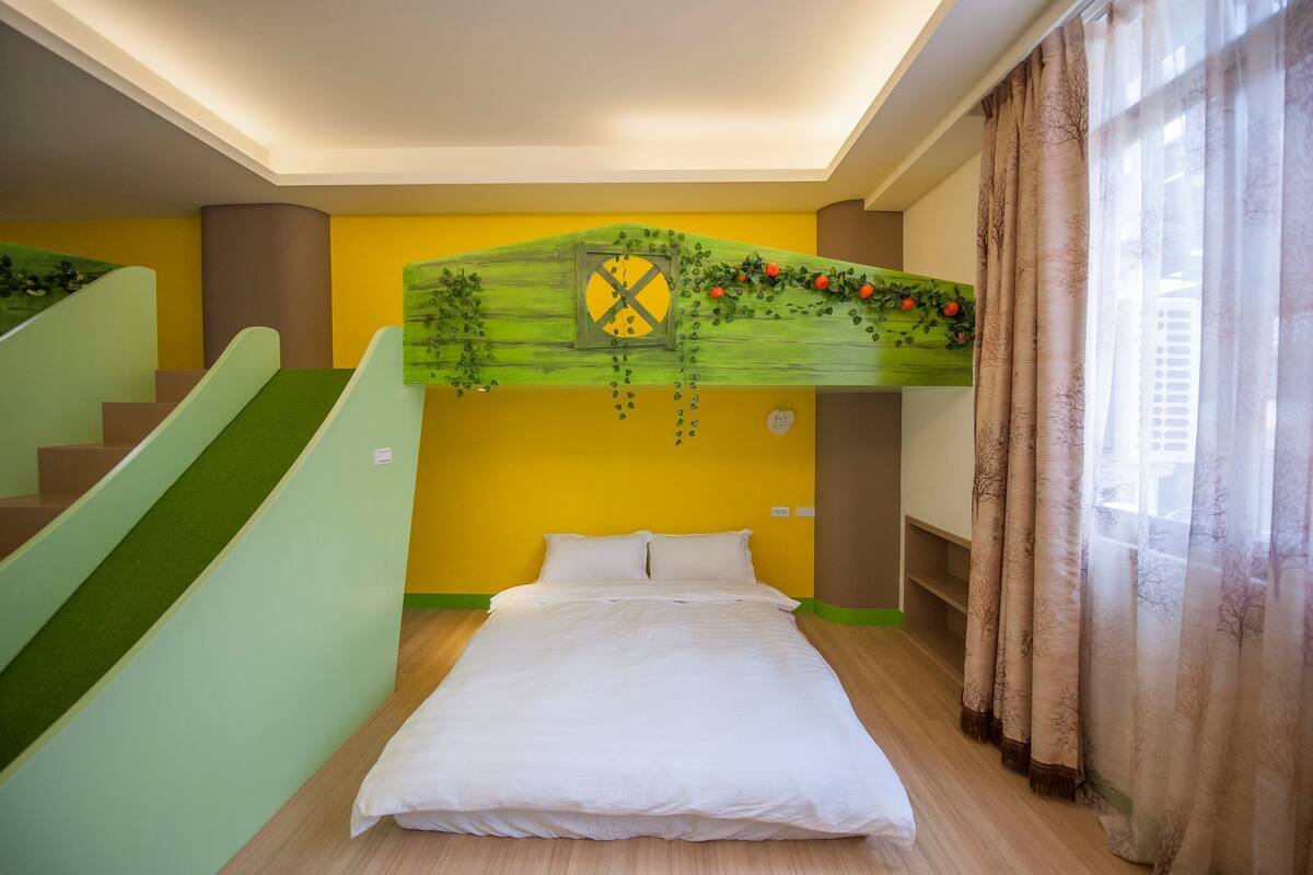 Ein Schlafzimmer mit einem Bett, einer grünen Wand mit einem Fenster und einer Treppe.