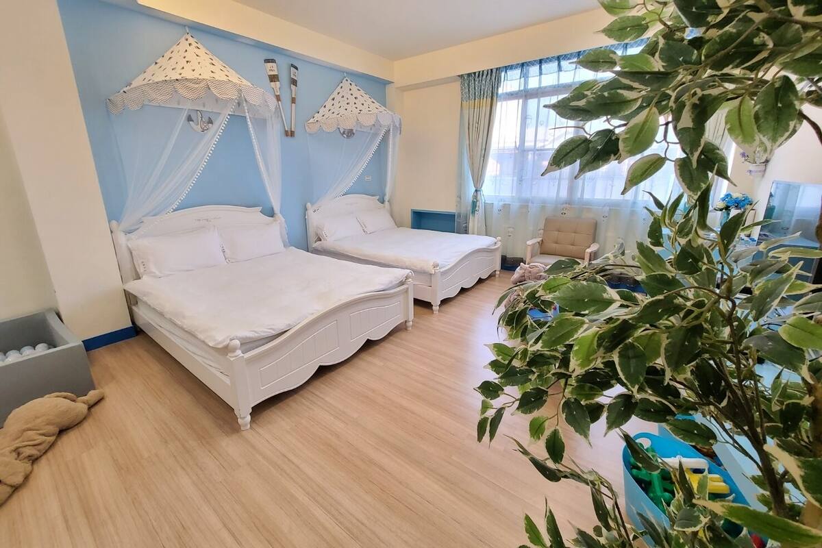 Ein Schlafzimmer mit zwei Betten, einem Sessel und einer großen Pflanze.
