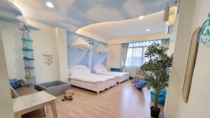 Una habitación infantil con dos camas, un área de juegos y una planta grande en maceta.