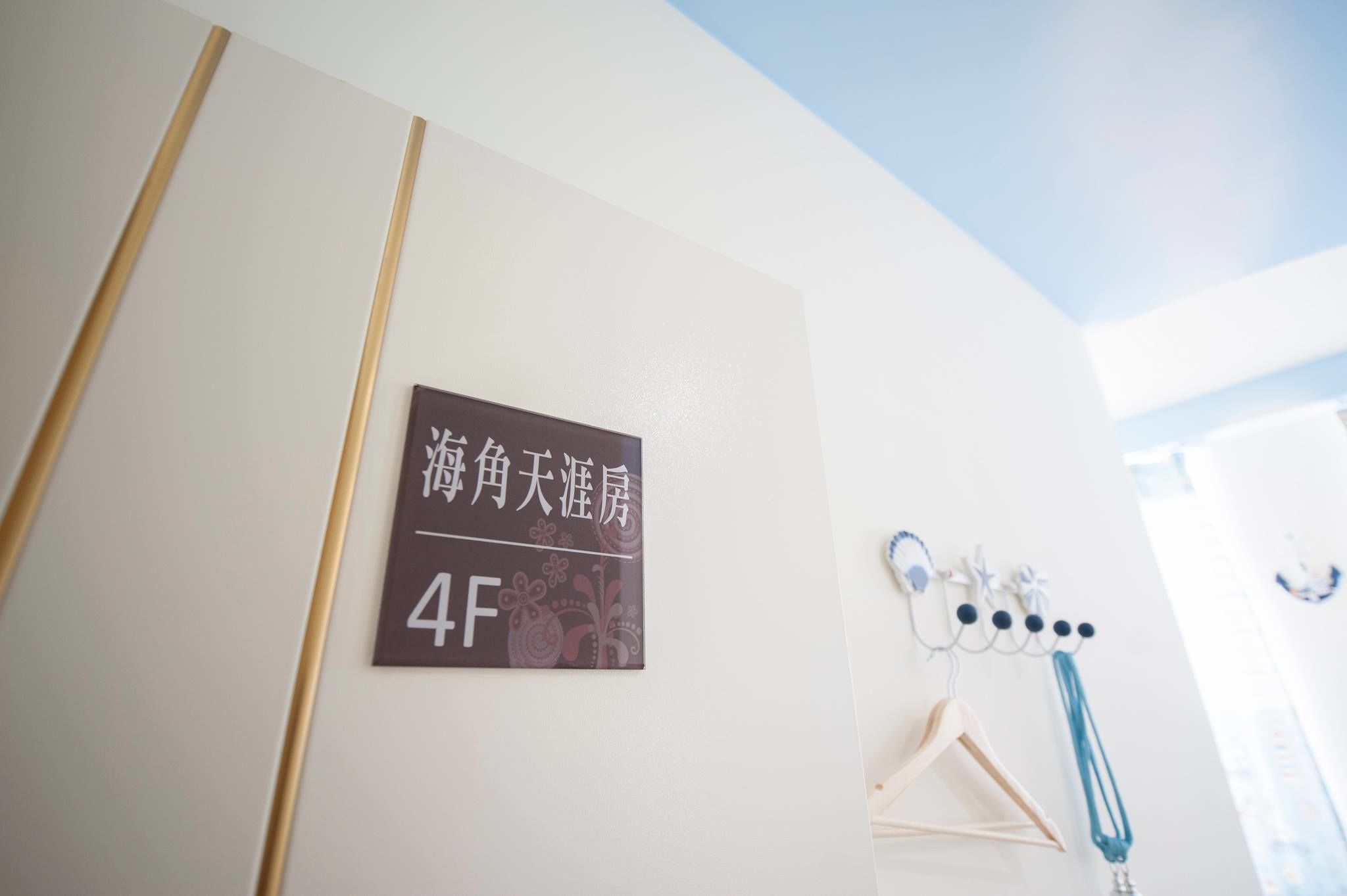 Eine Wand mit einem Schild, das Zimmer Nummer 4F anzeigt, und einem Kleiderhaken mit Kleiderbügeln.
