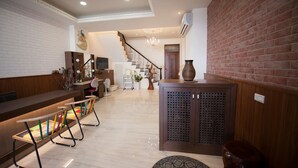 Un vestíbulo amplio con mostrador de recepción, una escalera y una pared decorativa.