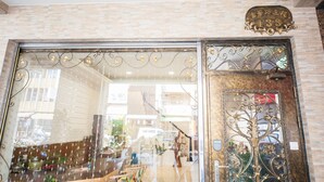 Entrada de un hotel con una puerta metálica decorativa y un cartel en la parte superior.