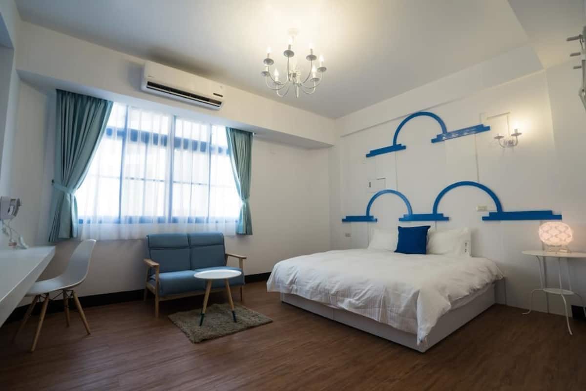 A modern bedroom with a large bed, a desk, and a chair.