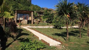 A modern house with a stone facade, a balcony, and a garden with a gravel path. - La Hacienda Old Grand Port Mauritius (Vieux Grand Port)