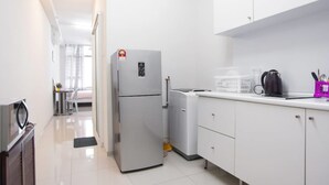 Una cocina moderna con armarios blancos, un refrigerador, una cafetera y un microondas.