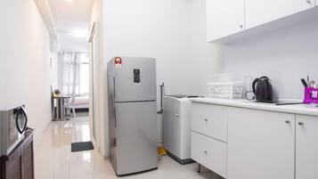 A modern kitchen with white cabinets, a refrigerator, a coffee maker, and a microwave.