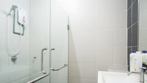 Un baño con cabina de ducha de vidrio, un lavamanos blanco y una barandilla.
