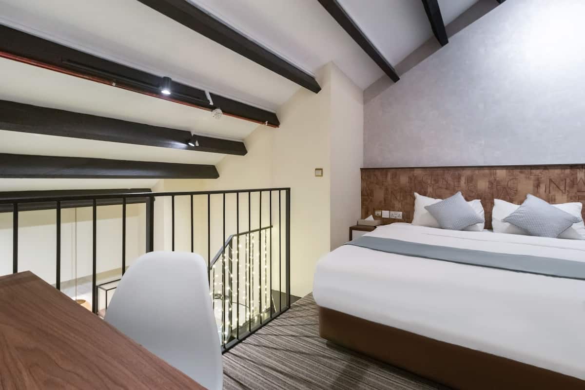 Une chambre d’hôtel moderne dotée d’un grand lit, d’un bureau et d’un escalier avec des rampes.