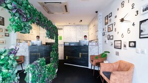 A reception area with a modern design, including a green leafy wall, a clock, and framed pictures on the wall. - Harbour Ville Hotel Hamilton - Lavender (Singapore)
