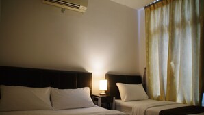 A hotel room with two beds, a nightstand with a lamp, and a window with curtains. - D'Esplanade City View Apartment (Johor Bahru)