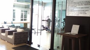 A gym entrance with glass doors, a reception area with wicker furniture, and a sign detailing gymnasium rules. - D'Esplanade City View Apartment (Johor Bahru)