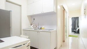 Une cuisine compacte avec des meubles blancs, un réfrigérateur et un petit plan de travail.