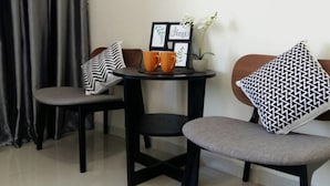 Une petite pièce moderne, avec deux chaises et une table, un tableau encadré et une plante en pot.