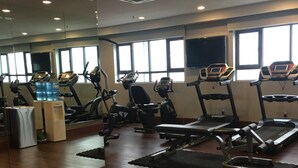 Ein Fitnessstudio mit Laufbändern, Crosstrainern und Trainingsmatten.