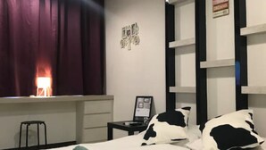 Ein Schlafzimmer mit Bett, Deckenventilator, Fenster mit Vorhängen, einer Wandablage und einer Wanddekoration.