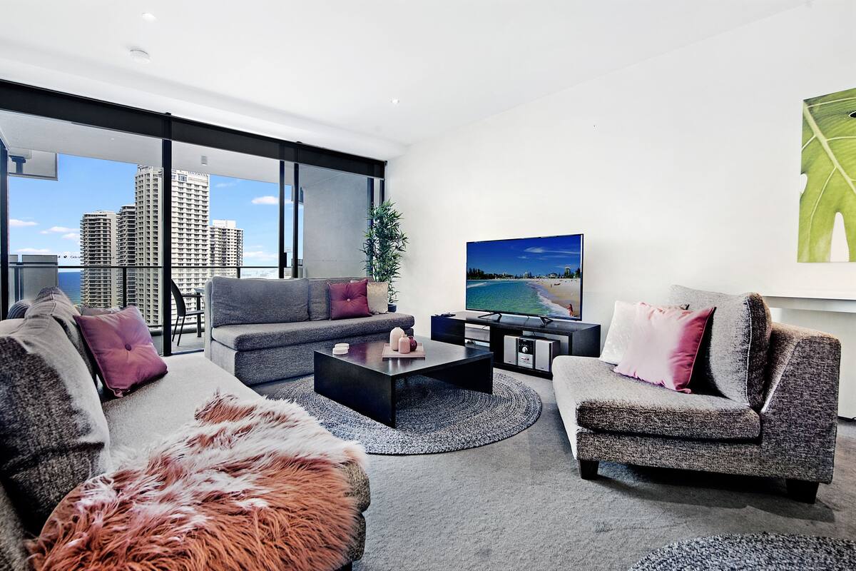 A modern living room with a grey sofa, a coffee table, and a large TV.