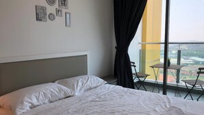 A hotel room with a bed, a balcony with a table and chairs, and a city view. - Evo Soho - Bandar Baru Bangi 2 (Bandar Baru Bangi)