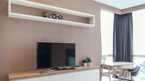A modern living room with a flat-screen TV, a wooden console, a dining area with a table and chairs, and a large window with curtains. - Pinnacle Studio - Heart of Petaling Jaya (Petaling Jaya)