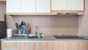 A modern kitchen with wooden cabinets, a stainless steel sink, and a dish rack. - Pinnacle Studio - Heart of Petaling Jaya (Petaling Jaya)