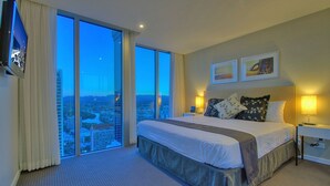 A hotel room with a large bed, a city view, and a flat-screen TV on the wall. - Orchid - Private Apartments (Surfers Paradise)