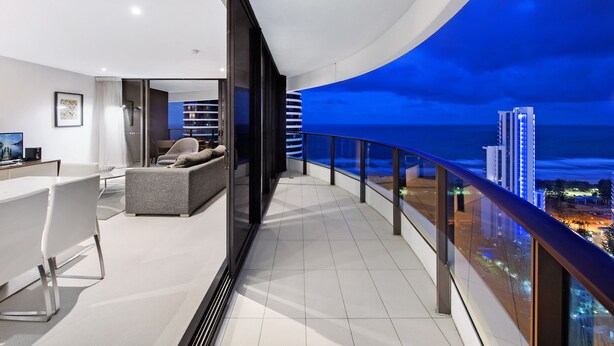 Un moderno salón con balcón que da a una vista nocturna de la ciudad.