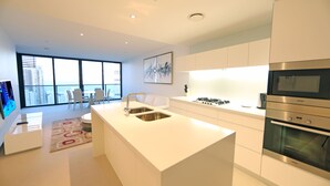Una cocina moderna con armarios blancos, una isla central con fregadero y un horno empotrado.