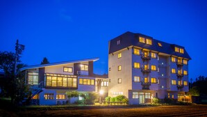 Un hotel moderno con varios pisos, amplias ventanas y una fachada bien iluminada.
