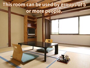 Una habitación con esteras tatami, una mesa baja y sillas, ideal para grupos de 5 personas o más.