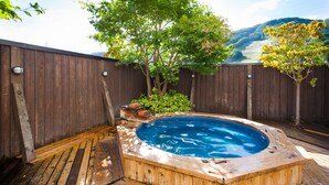 Una terraza de madera con un jacuzzi rodeado por una valla de madera y árboles.