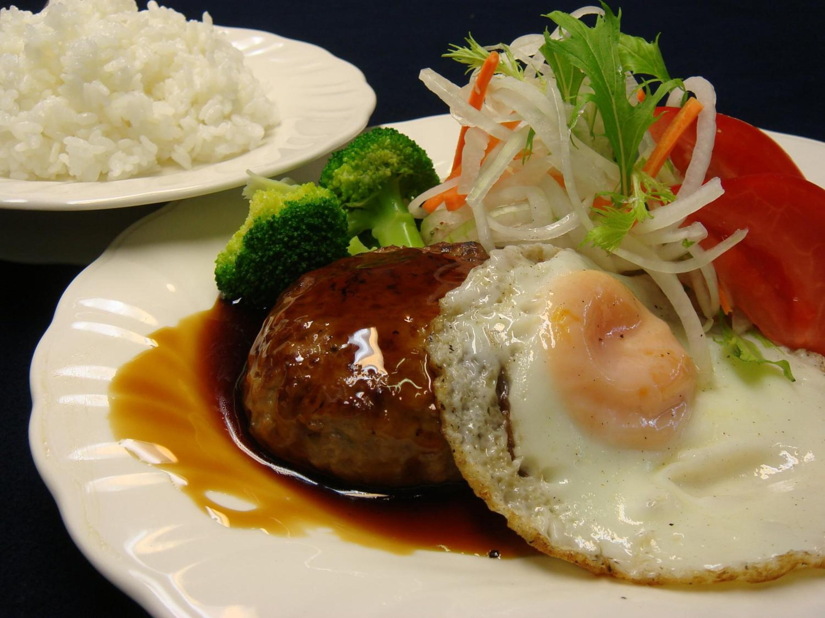 A plate with a meat patty, egg, and vegetables.