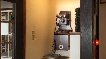 Een kleine kamer met een telefoon in vintage-stijl en een tafeltje met een boek.