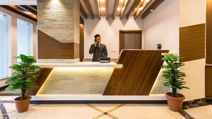 A reception desk with a modern design, wooden accents, and potted plants. - Hotel Landmark Kathmandu (Kathmandu)