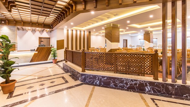 A reception area with a marble floor, wooden reception desk, and a seating area with tables and chairs. - Hotel Landmark Kathmandu (Kathmandu)