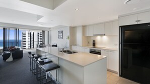 A modern kitchen with a large island, bar stools, and a view of the cityscape.