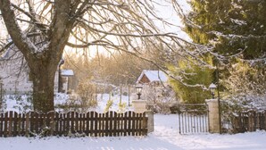 A snow-covered landscape with a wooden fence, a gate, and a building in the background.