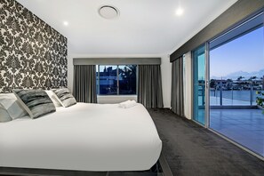 Een moderne hotelkamer met een groot bed, uitzicht op de stad en een balkon.