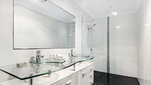 Ein modernes Badezimmer mit zwei Glaswaschbecken, einem großen Spiegel und einer Duschkabine aus Glas.