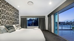 Ein modernes Hotelzimmer mit einem großen Bett, Blick auf die Stadt und einem Balkon.