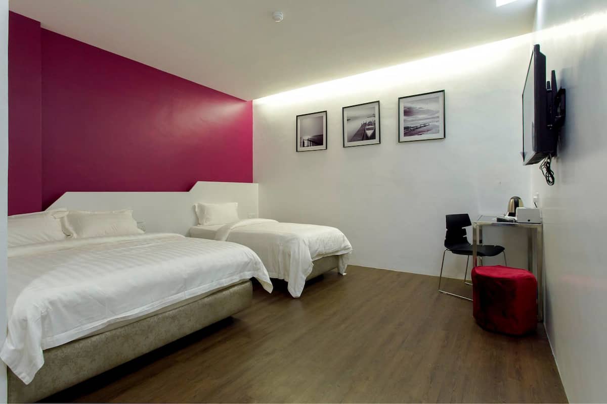 A modern hotel room with two beds, a desk, a chair, and a TV mounted on the wall.