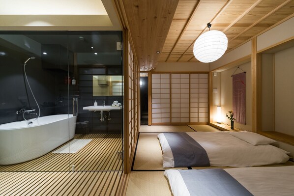 A modern Japanese-style bedroom with a large bed, a separate bathroom with a bathtub, and a sliding shoji screen door. - Lica's Room (Kyoto)