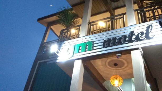 L’entrée d’un hôtel, avec une enseigne indiquant « motel » et un escalier menant à l’entrée.