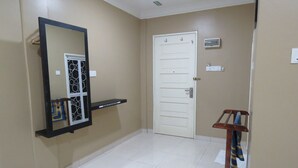 Un couloir avec une porte blanche, un miroir et une petite étagère.
