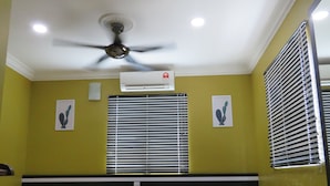 Une chambre d’hôtel équipée d’un lit, d’une petite table, d’un climatiseur et d’un ventilateur de plafond.