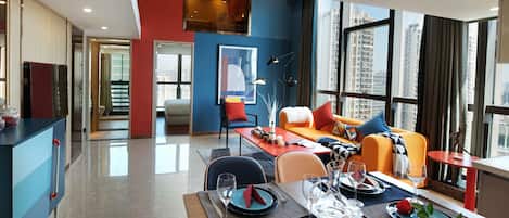 A modern dining area with a table set for four, a sofa, and a city view through large windows.