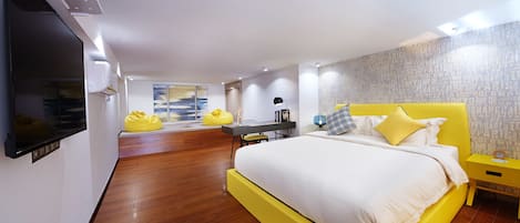 A modern bedroom with a large bed, a desk, and a TV.