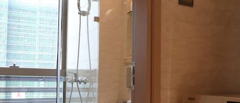 A modern bathroom with a glass shower enclosure, a toilet, and a built-in washing machine.
