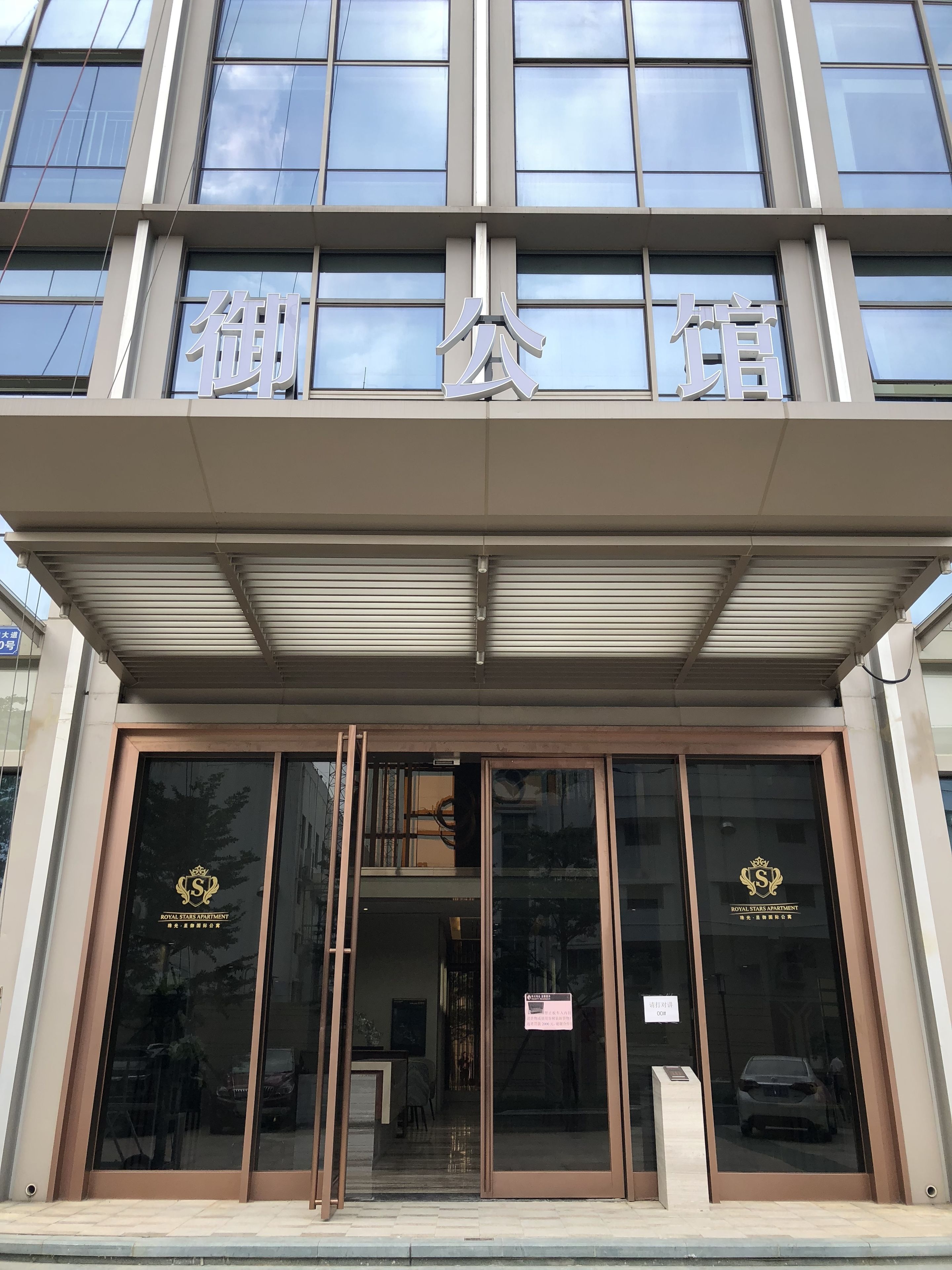 Un edificio con amplios ventanales y un cartel sobre la entrada.